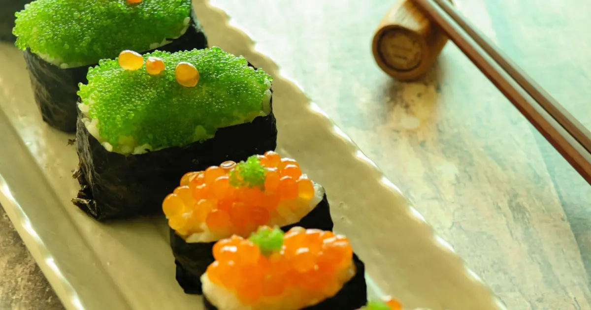 Colorful Tobiko Sushi roll with bright orange flying fish eggs sprinkled on top, showcasing vibrant sushi presentation with salmon, cucumber, and nori.