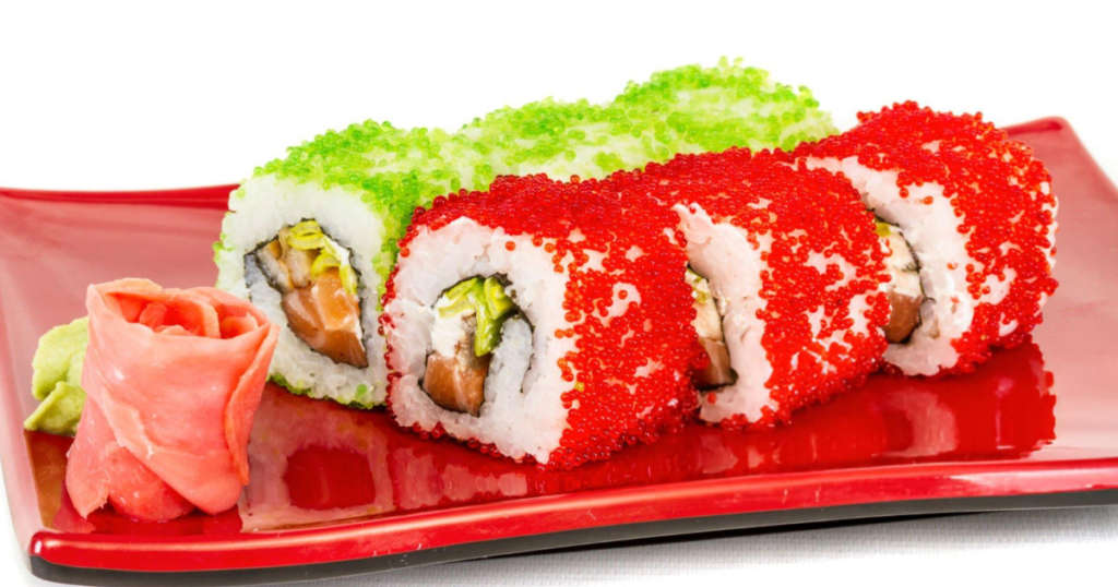 Macro shot of bright orange flying fish eggs (tobiko) showing their glossy, individual spherical texture against a blurred sushi background
